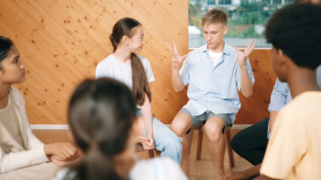 Boy sharing experiences during a group therapy for teens.